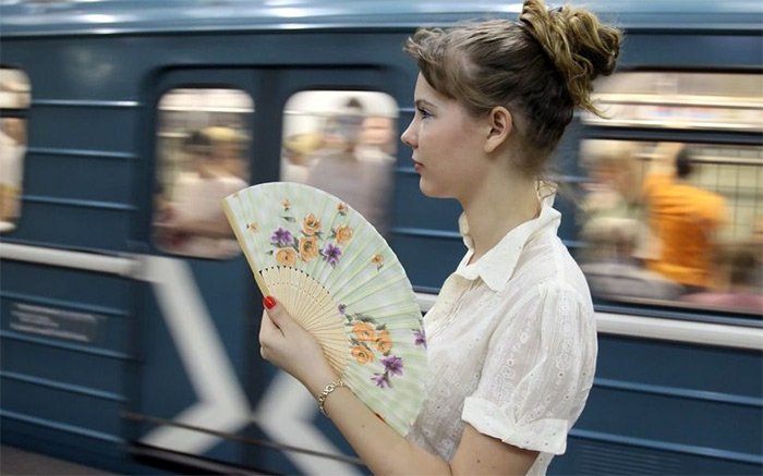 Girl with a fan in the summer heat